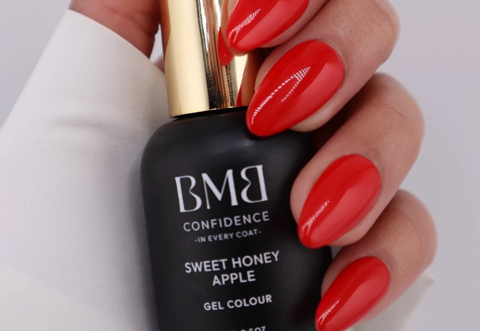 Bella Mano Beauty gel colour bottle held in a hand with red nails.